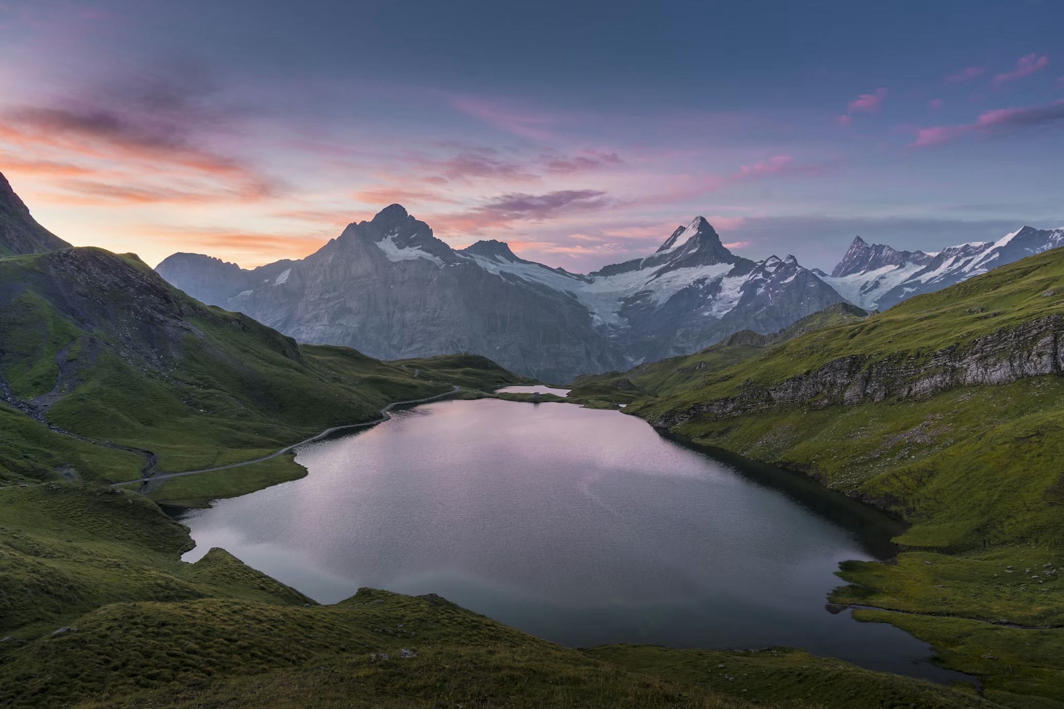 Bachalpsee alpine lake above Grindelwald at sunrise reflecting pink sky and Schreckhorn peaks Bernese Oberland Switzerland