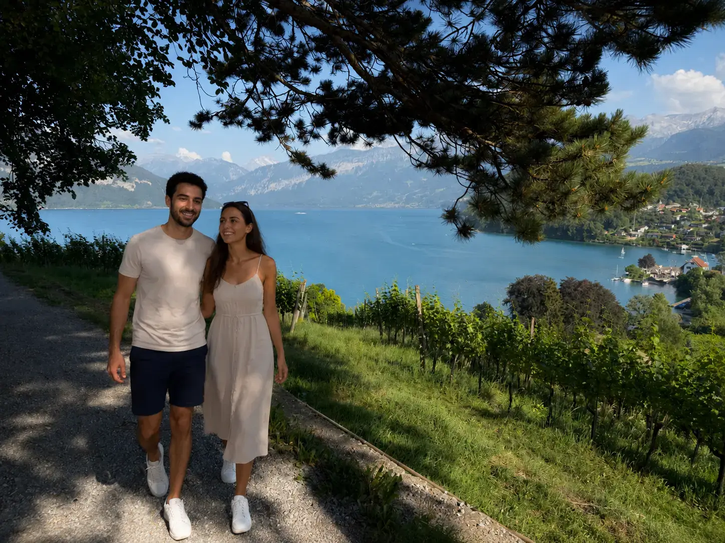Couple walking the vineyard path above turquoise Lake Thun in Spiez, an easy wine walk near Interlaken