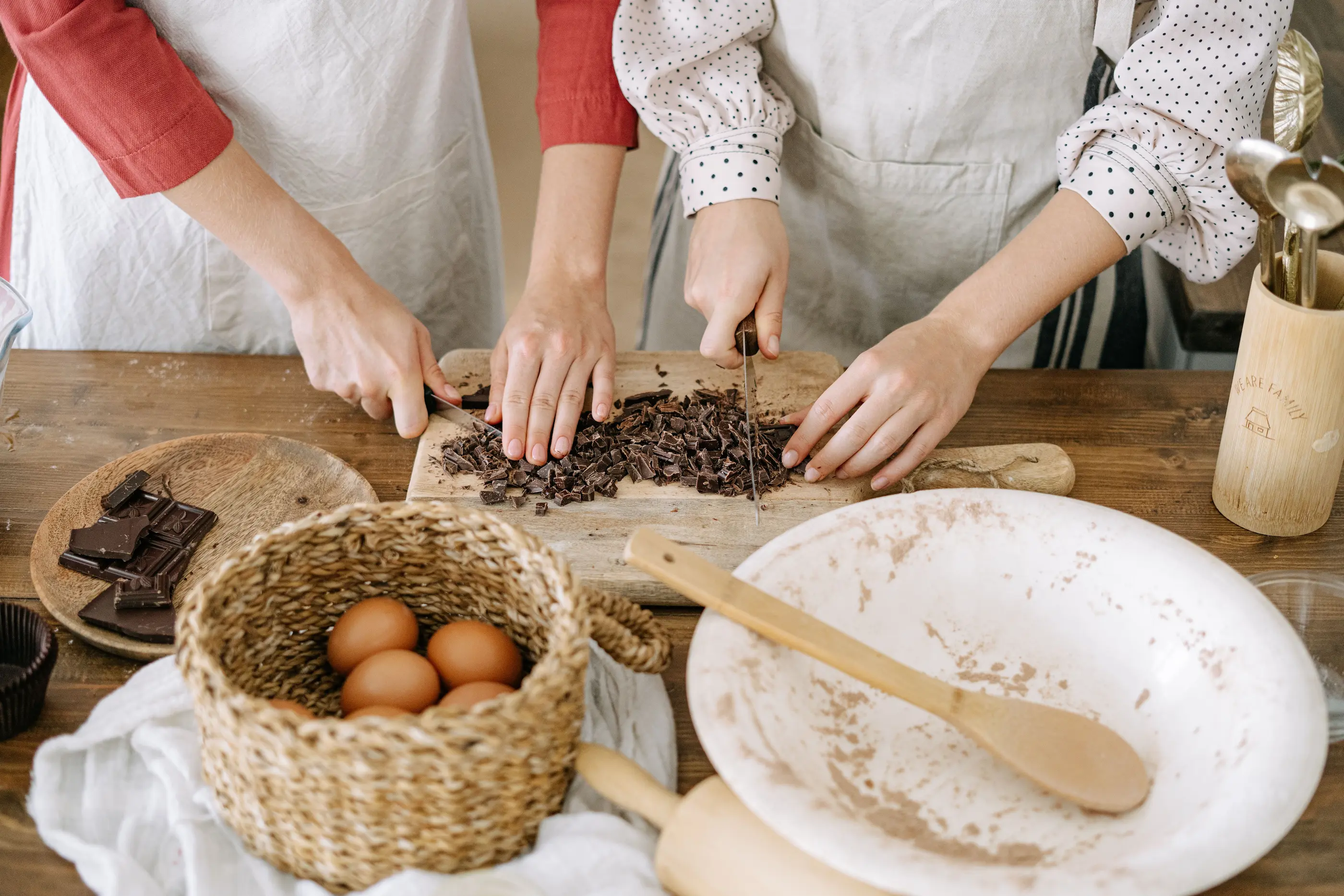 Two people chopping dark chocolate at a wooden table, a chocolate workshop rather than a museum visit